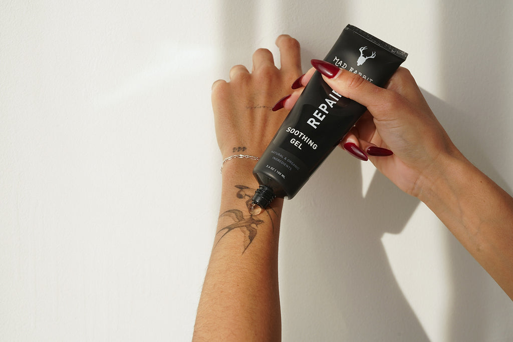 Female hands putting Mad Rabbit soothing gel on an arm
tattoo