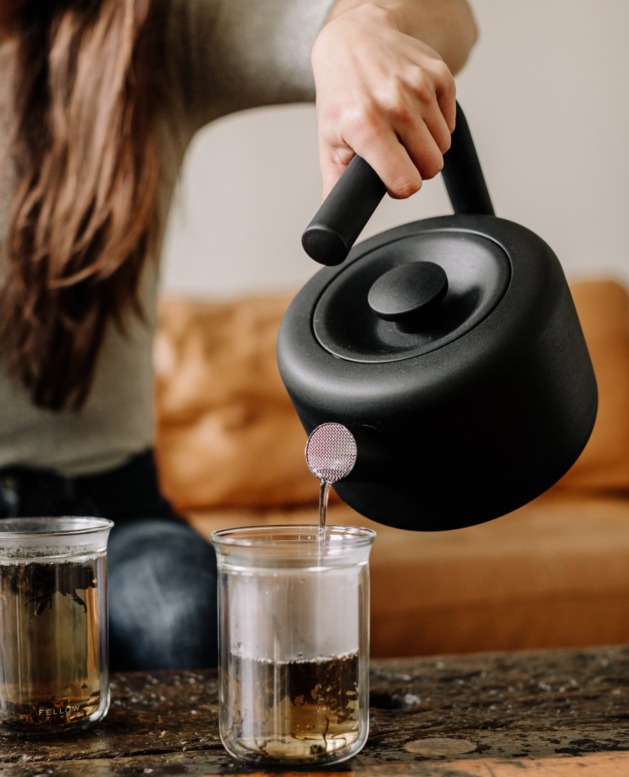 A model pours hot water out of the Clyde stovetop tea kettle into a Stagg
Tasting
Glass.