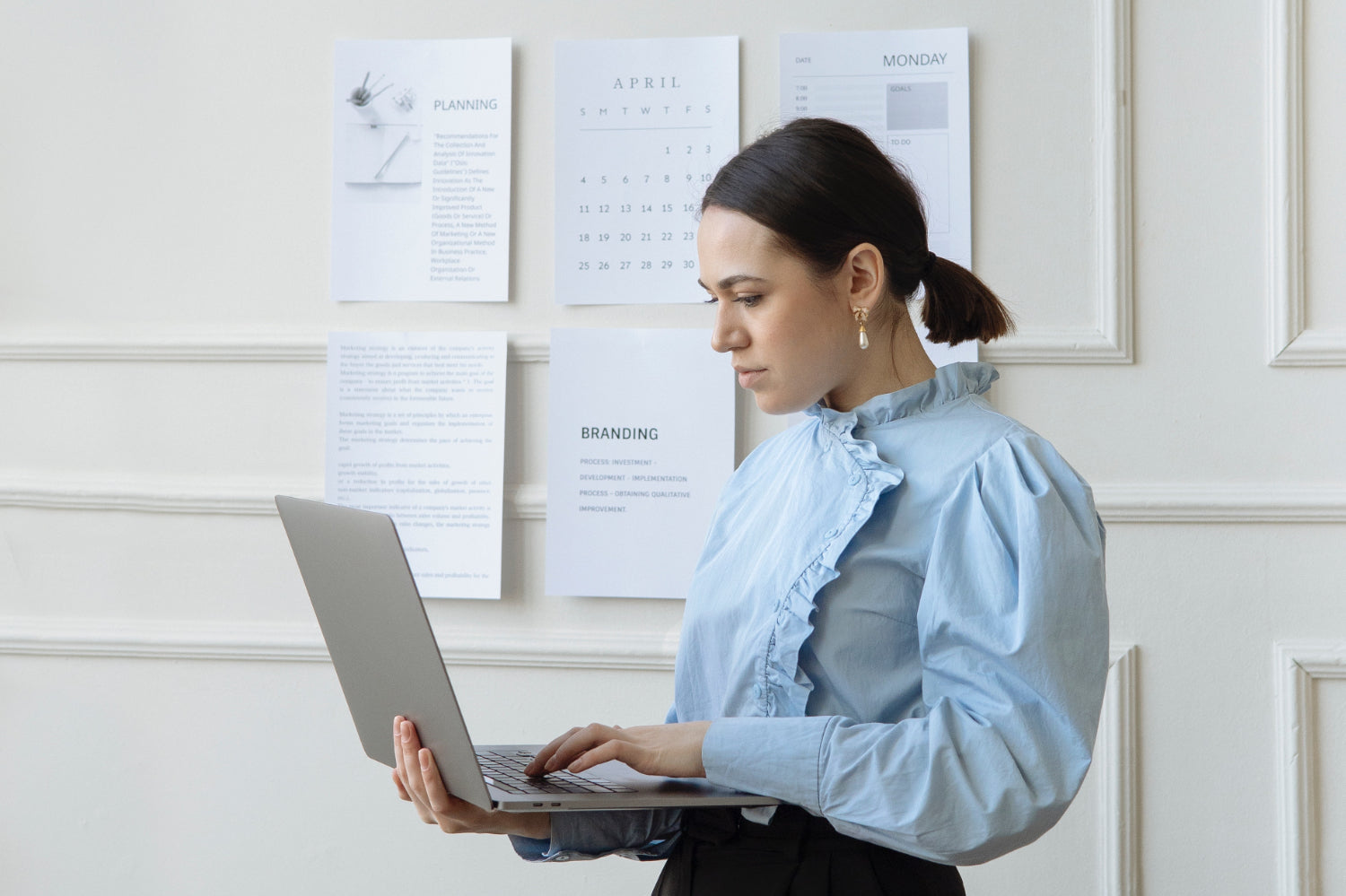 A woman looks at a laptop against a wall covered in business plan
documents