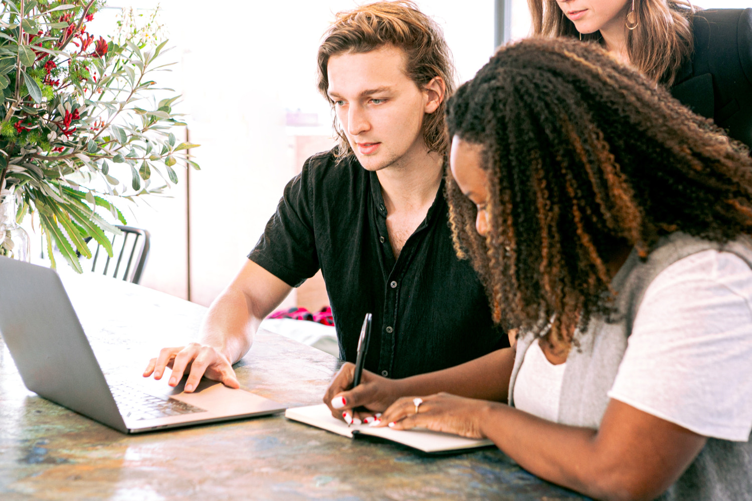 Three people gather around a laptop to work on a business
plan