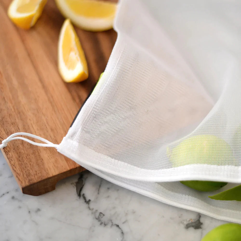 Mesh bag for fruits and vegetables sits on a cutting board with
fruit