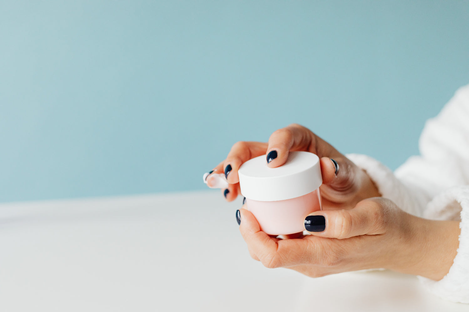 Hands hold an unmarked jar of skin
cream
