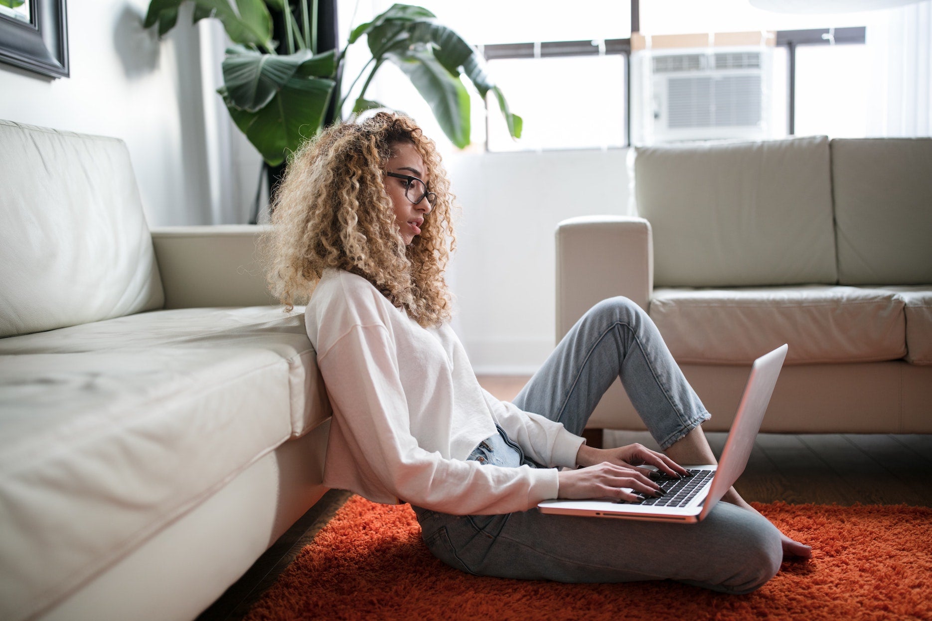 A woman does research on a laptop sitting on the
floor