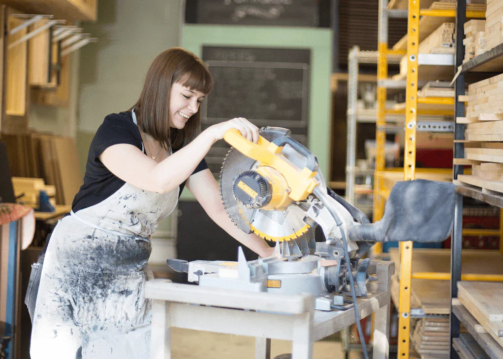 A woman uses a power saw in a
workshop