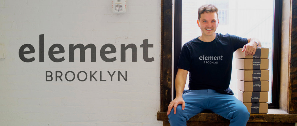 Element Brooklyn 的首席执行官兼创始人坐在公司仓库的窗台上，手里拿着装满的订单