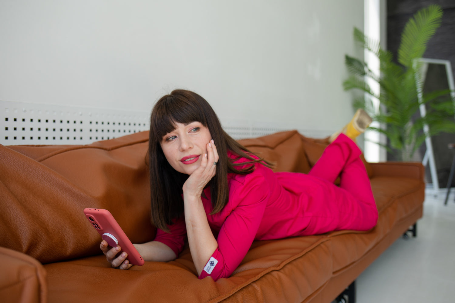 女人躺在沙发上，手里拿着手机