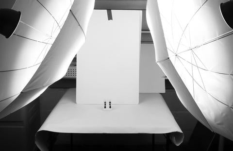 产品摄影工作室设置，配有白色扫帚、产品和雨伞照明扩散器。