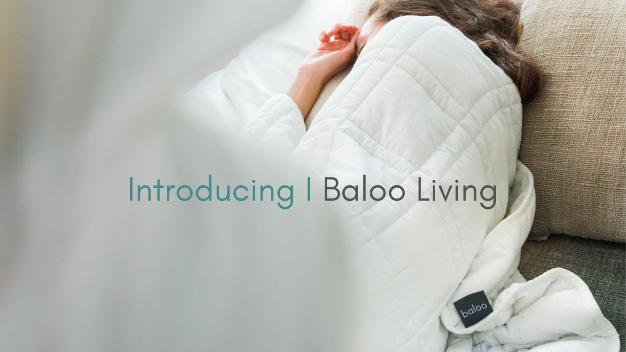 Baloo Living 广告中，一个人睡在白色 Baloo 加重毯子下。