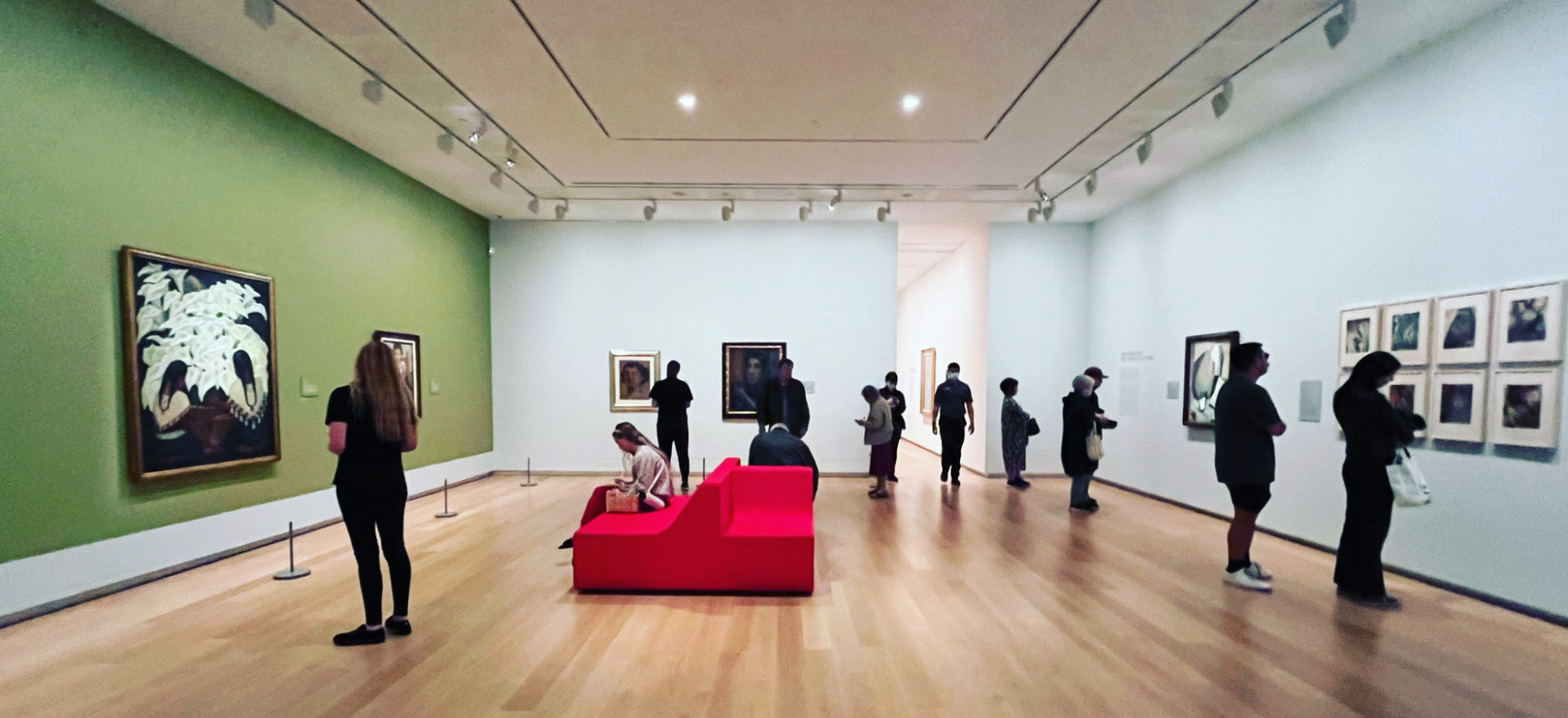 艺术画廊空间的示例,墙上挂着画作,人们正在观看它们。